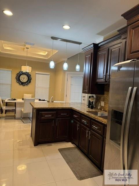 kitchen featuring stainless steel refrigerator with ice dispenser, dark brown cabinetry, sink, decorative light fixtures, and backsplash