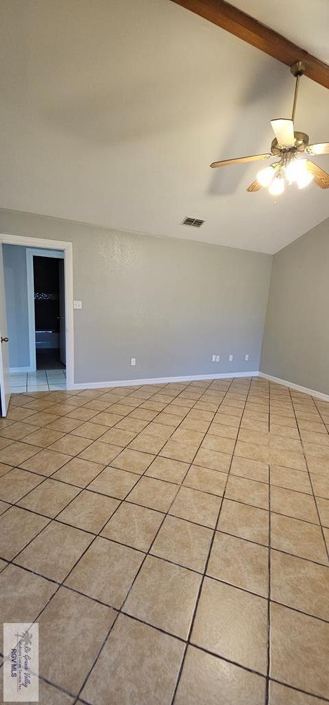 spare room with light tile patterned flooring, ceiling fan, and vaulted ceiling with beams