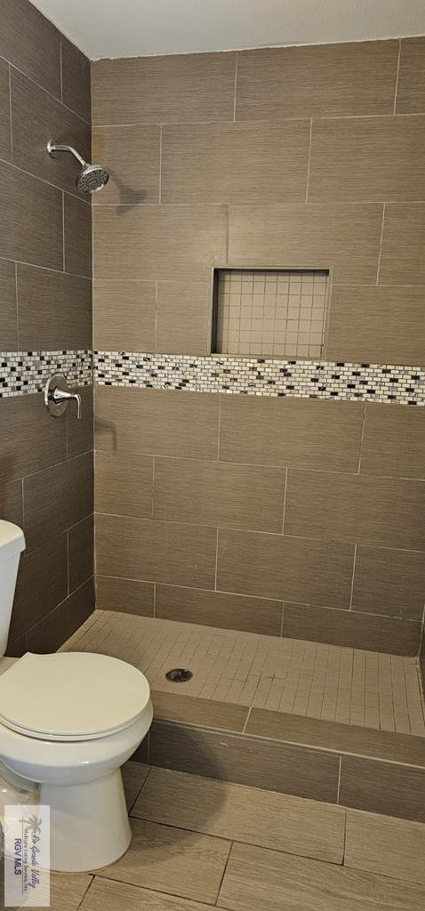 bathroom featuring tiled shower and toilet