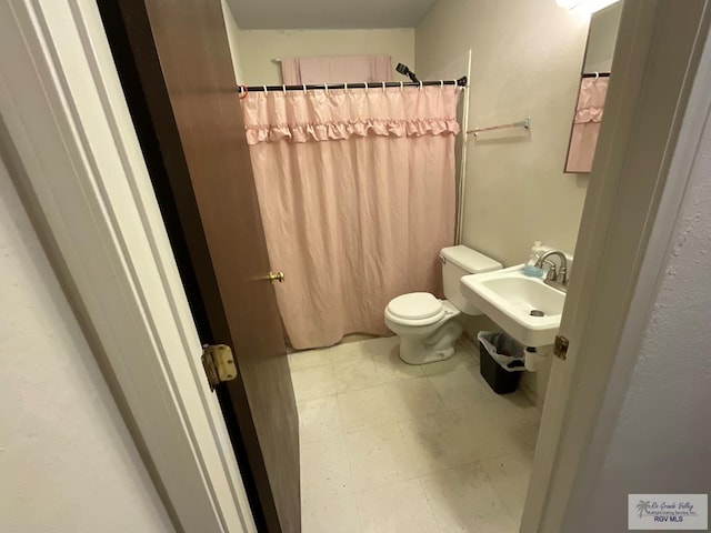 bathroom featuring sink, a shower with shower curtain, and toilet