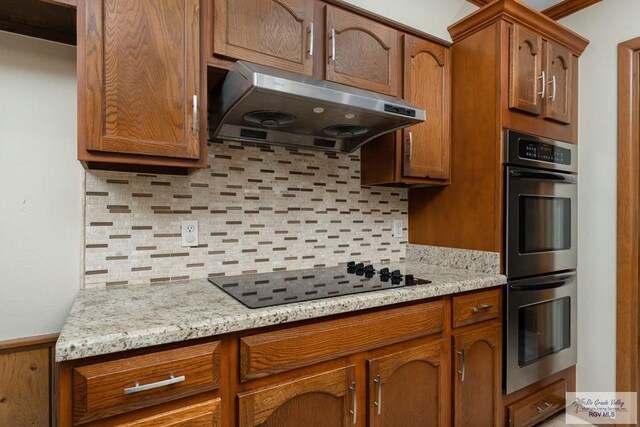 kitchen with double oven, black electric cooktop, tasteful backsplash, and exhaust hood