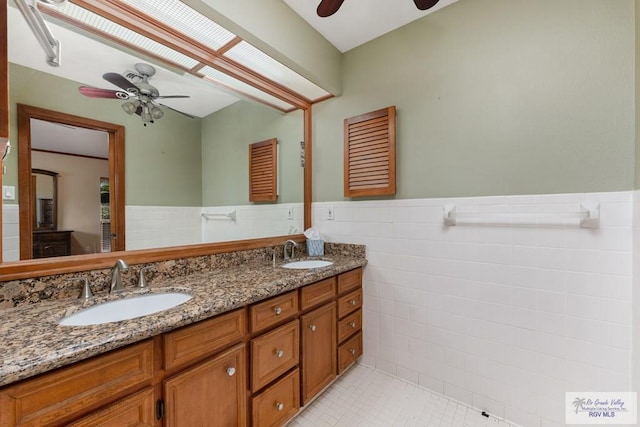 bathroom featuring tile patterned floors, vanity, tile walls, and a skylight