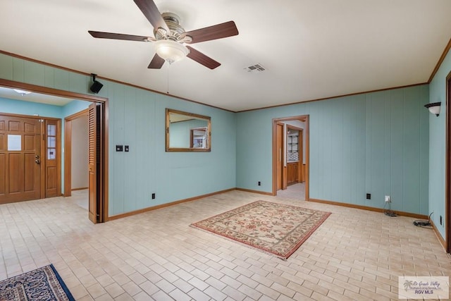 empty room featuring ceiling fan, crown molding, and wood walls