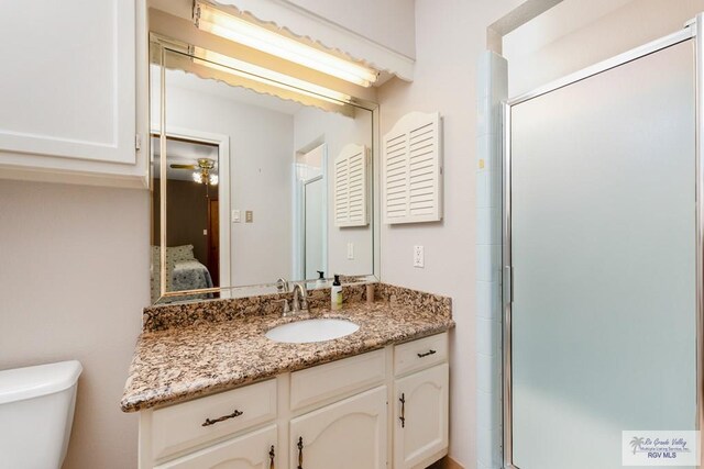 bathroom featuring vanity, an enclosed shower, and toilet