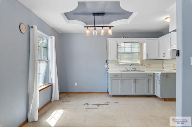 1537 E Harrison St, Brownsville, TX 78520 - kitchen with a sink, gray cabinets, a raised ceiling, light countertops, and decorative backsplash