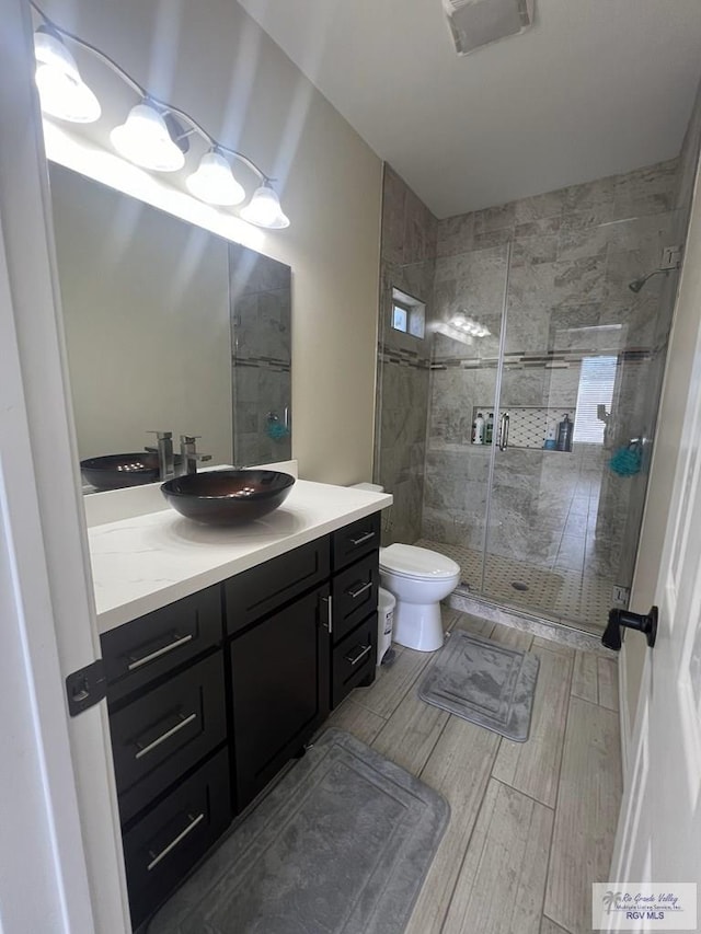 bathroom with hardwood / wood-style floors, vanity, toilet, and a shower with door