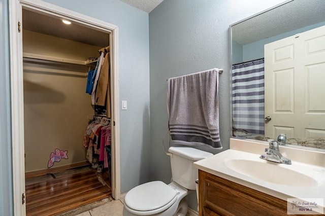 3053 Fairfield Dr, Brownsville, TX 78526 - bathroom featuring vanity, a walk in closet, a textured ceiling, and tile patterned floors