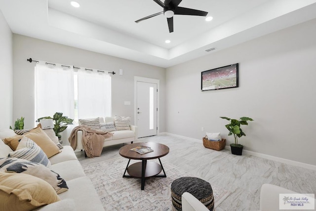 carpeted living room featuring a tray ceiling and ceiling fan