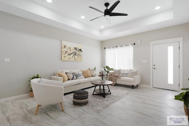 living room featuring ceiling fan and a raised ceiling