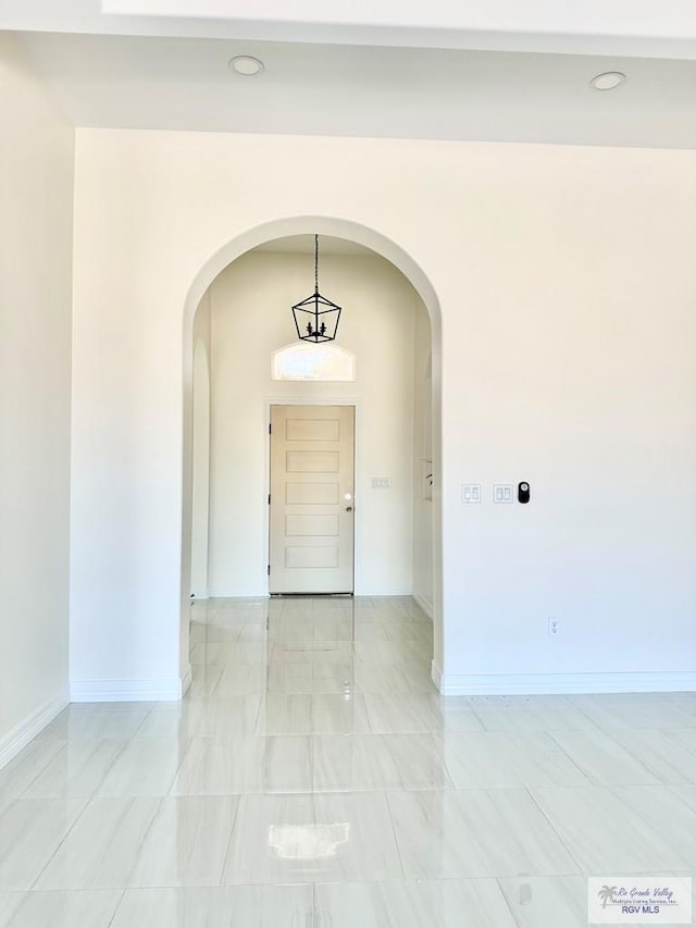 interior space featuring baseboards, arched walkways, and recessed lighting