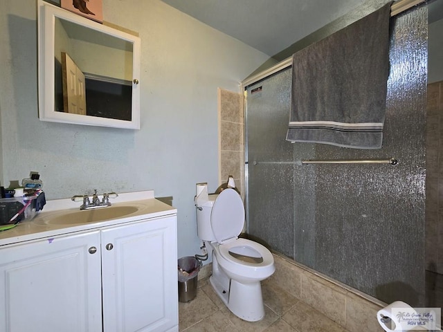 bathroom featuring tile patterned flooring, vanity, toilet, and a shower with door