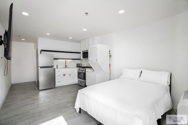 bedroom with light hardwood / wood-style flooring, stainless steel refrigerator, and sink