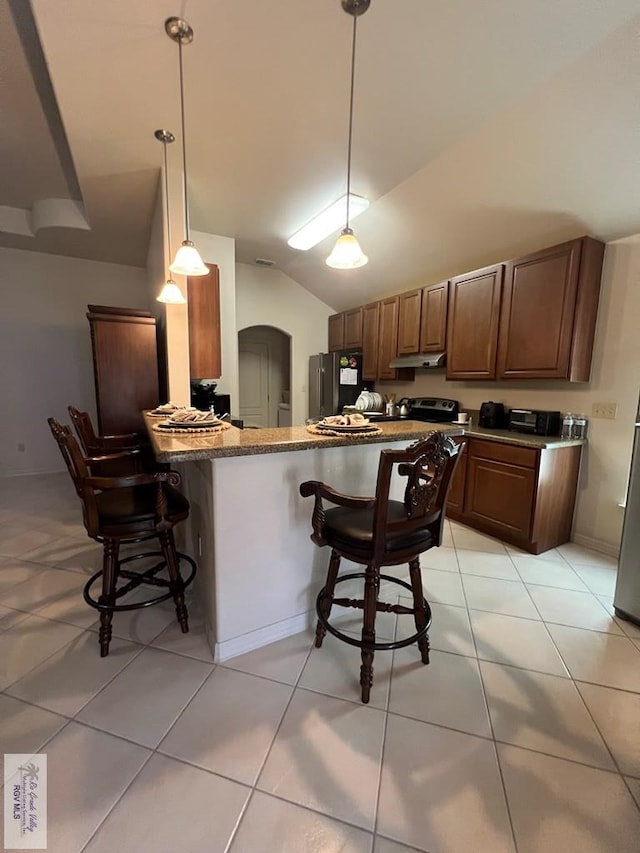 kitchen featuring arched walkways, a breakfast bar area, a peninsula, and lofted ceiling