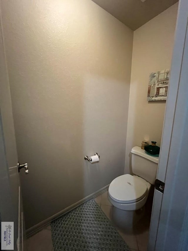 bathroom featuring toilet, baseboards, and tile patterned flooring