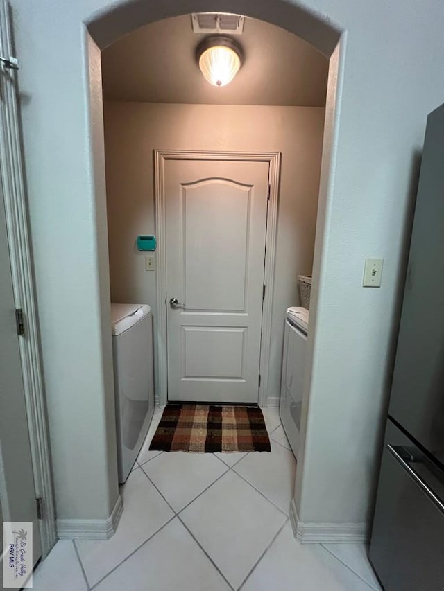 laundry area with laundry area, arched walkways, tile patterned flooring, and washer and dryer