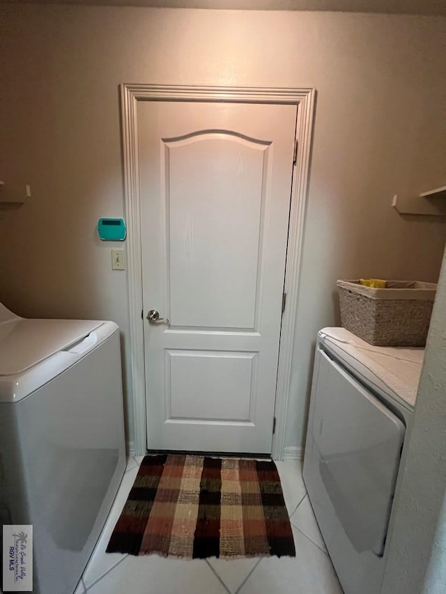 clothes washing area featuring washer / dryer, light tile patterned floors, and laundry area