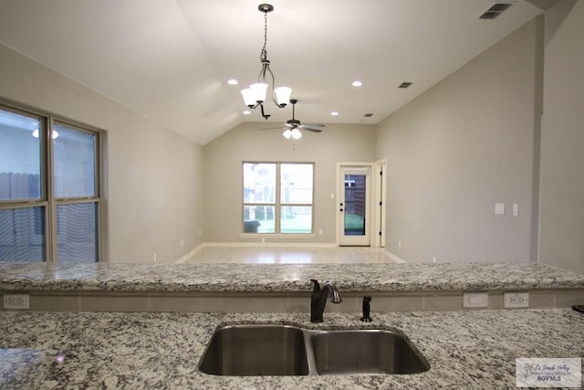 kitchen with visible vents, lofted ceiling, light stone counters, pendant lighting, and a sink