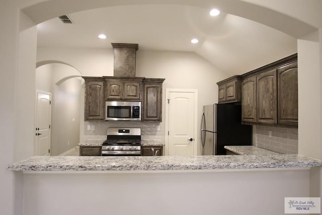 kitchen featuring stainless steel appliances, visible vents, dark brown cabinetry, and light stone counters