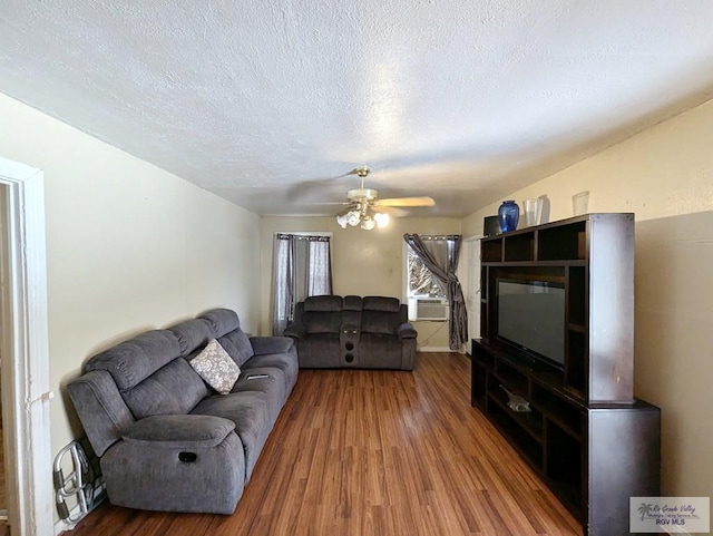 living room featuring a ceiling fan, cooling unit, a textured ceiling, and wood finished floors