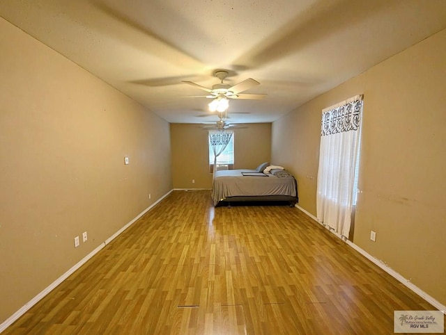 unfurnished bedroom featuring a ceiling fan, light wood-style flooring, and baseboards