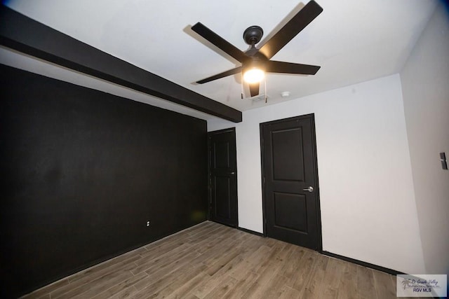 unfurnished bedroom with light wood-style floors, a ceiling fan, and beamed ceiling