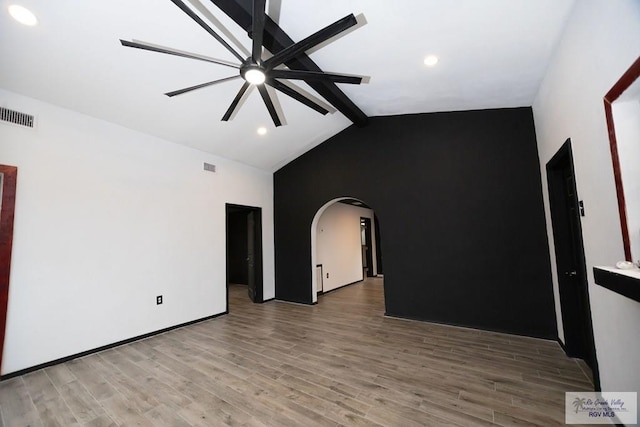 spare room featuring arched walkways, visible vents, lofted ceiling with beams, ceiling fan, and wood finished floors