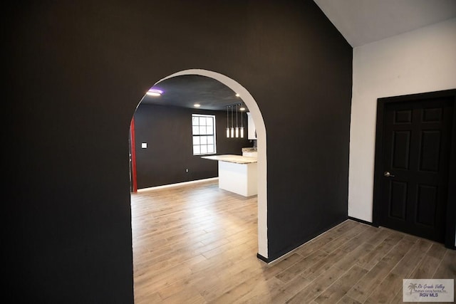 interior space featuring arched walkways, wood finished floors, and baseboards