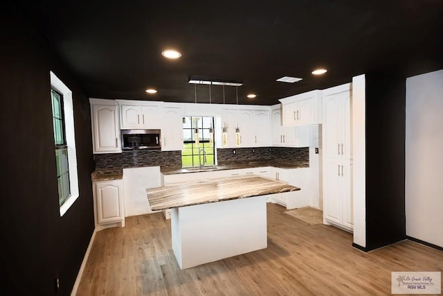 kitchen with a center island, white cabinets, stainless steel microwave, and a sink