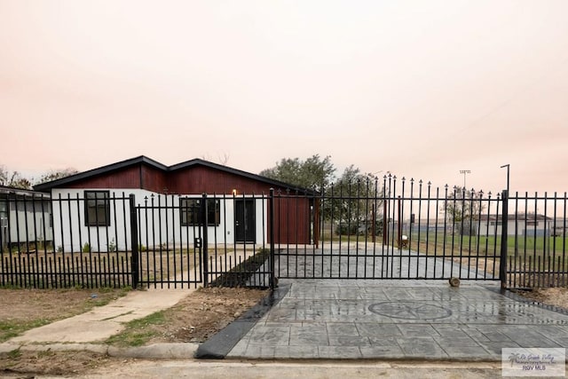 gate at dusk featuring a fenced front yard