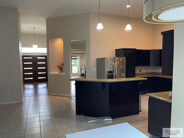 kitchen with pendant lighting, a breakfast bar, stainless steel fridge, and light tile patterned floors