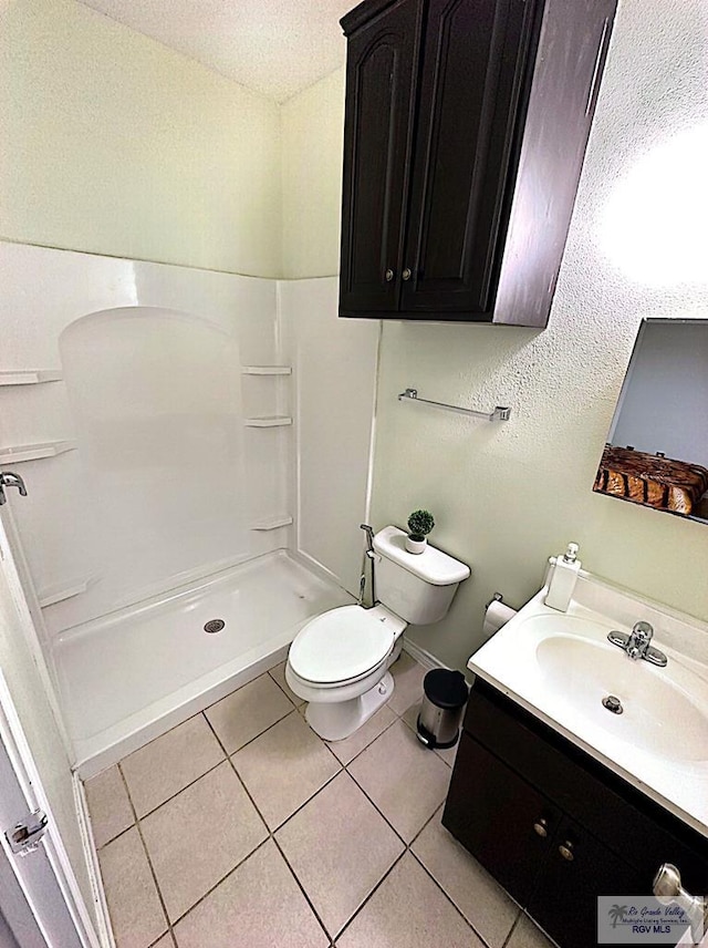 bathroom with toilet, vanity, tile patterned floors, and walk in shower