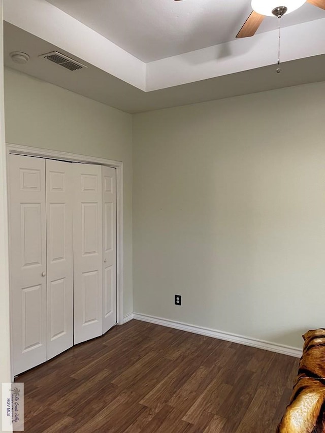 unfurnished bedroom featuring dark hardwood / wood-style floors, ceiling fan, and a closet