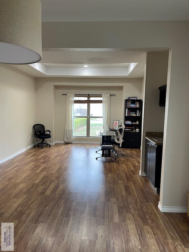 interior space with a tray ceiling and dark hardwood / wood-style floors