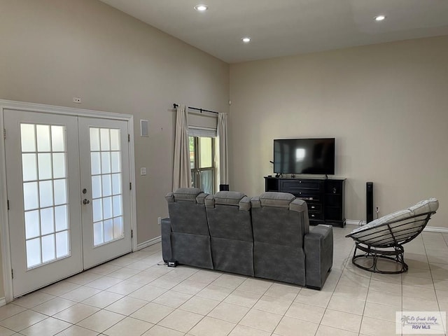 living room with light tile patterned floors, a towering ceiling, and french doors