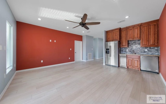 kitchen featuring appliances with stainless steel finishes, sink, backsplash, ceiling fan, and light wood-type flooring