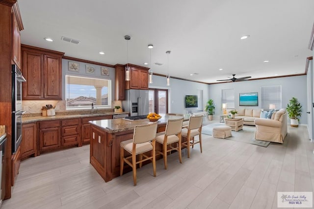 kitchen featuring pendant lighting, sink, appliances with stainless steel finishes, a kitchen breakfast bar, and a kitchen island