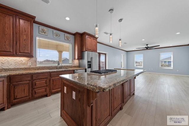 kitchen featuring a kitchen island, appliances with stainless steel finishes, sink, hanging light fixtures, and a healthy amount of sunlight