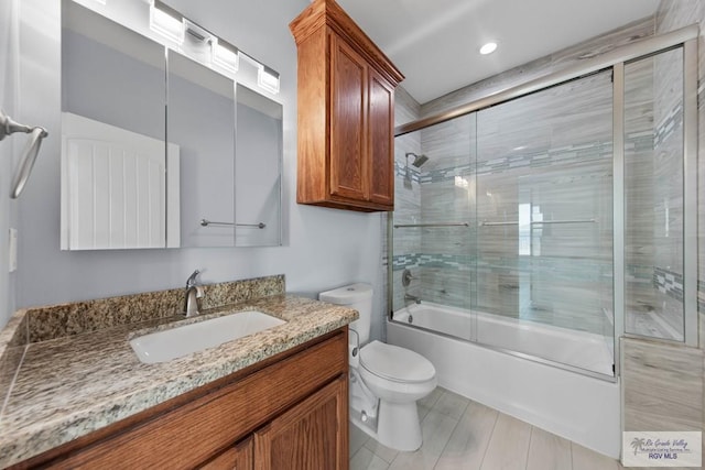 full bathroom featuring vanity, shower / bath combination with glass door, and toilet