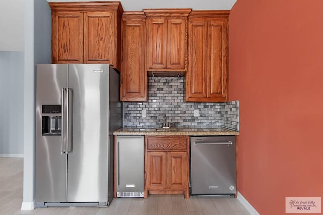 kitchen featuring stainless steel appliances, tasteful backsplash, sink, and light stone counters