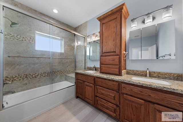 bathroom with hardwood / wood-style flooring, vanity, and shower / bath combination with glass door