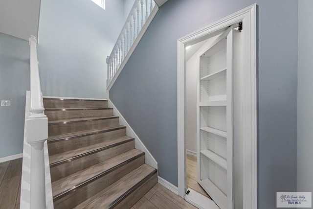 stairs featuring hardwood / wood-style floors and built in features