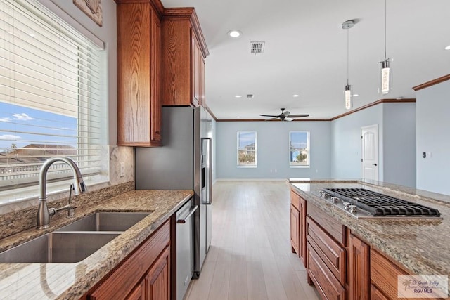 kitchen with stainless steel appliances, light stone countertops, hanging light fixtures, and sink