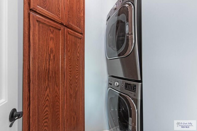 laundry area featuring stacked washer / dryer and cabinets