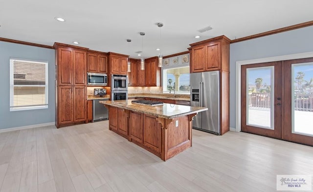 kitchen with pendant lighting, a kitchen breakfast bar, stainless steel appliances, a center island, and light stone countertops