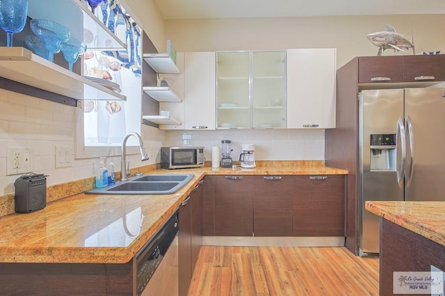 kitchen featuring white cabinets, appliances with stainless steel finishes, dark brown cabinetry, and light hardwood / wood-style flooring