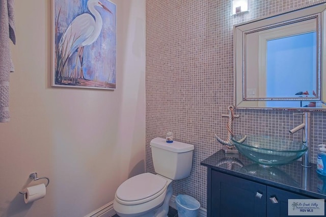 bathroom featuring vanity, toilet, and tile walls