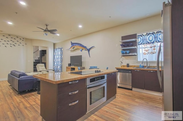 kitchen with a center island, ceiling fan, light wood-type flooring, appliances with stainless steel finishes, and dark brown cabinets