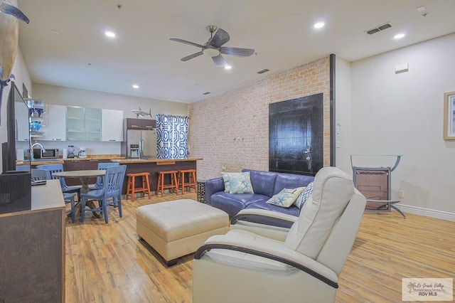 living room featuring ceiling fan, light hardwood / wood-style floors, and sink