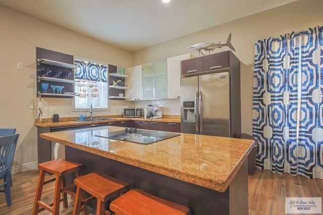 kitchen with a kitchen bar, appliances with stainless steel finishes, decorative backsplash, sink, and hardwood / wood-style floors