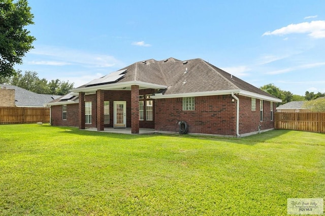 back of property with a lawn, a patio, and solar panels